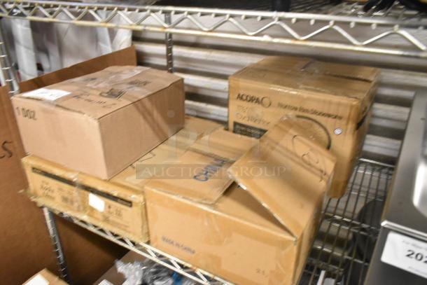 Boxes containing brand new items on a shelf, including Acopa Gardenia Rocks Glasses, Oneida bowls, and Acopa Stoneware Platters.