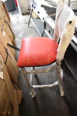 Lancaster Table & Seating black ladder bar height chair with red seat cushion, new condition, protective wrapping visible.