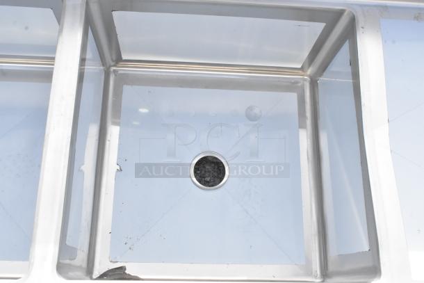 BRAND NEW Regency 600S42424224 stainless steel 4 bay sink with dual drain boards, showing scratch and dent condition. No legs.