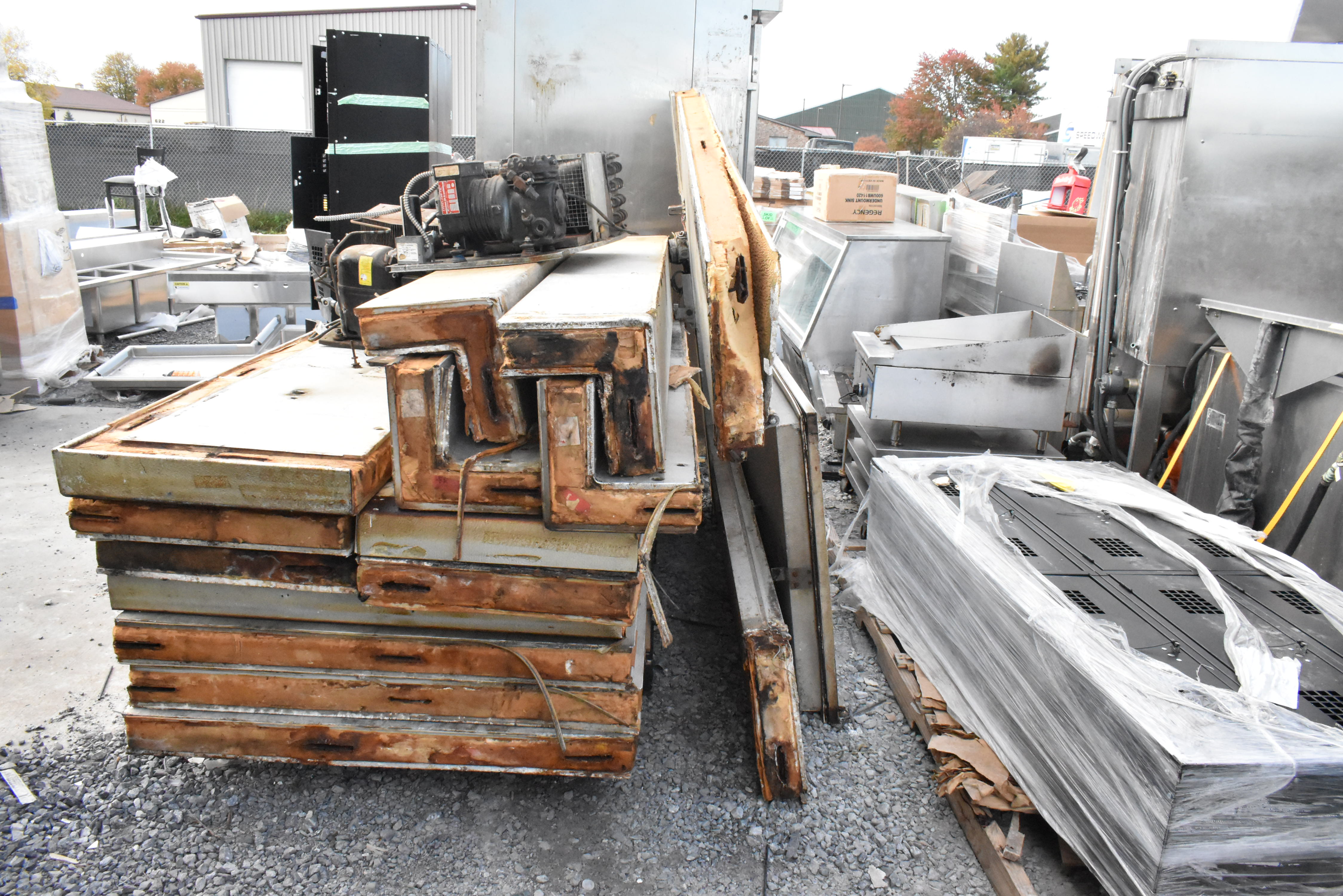 Heavily damaged walk-in cooler showing severe rust and panel separation