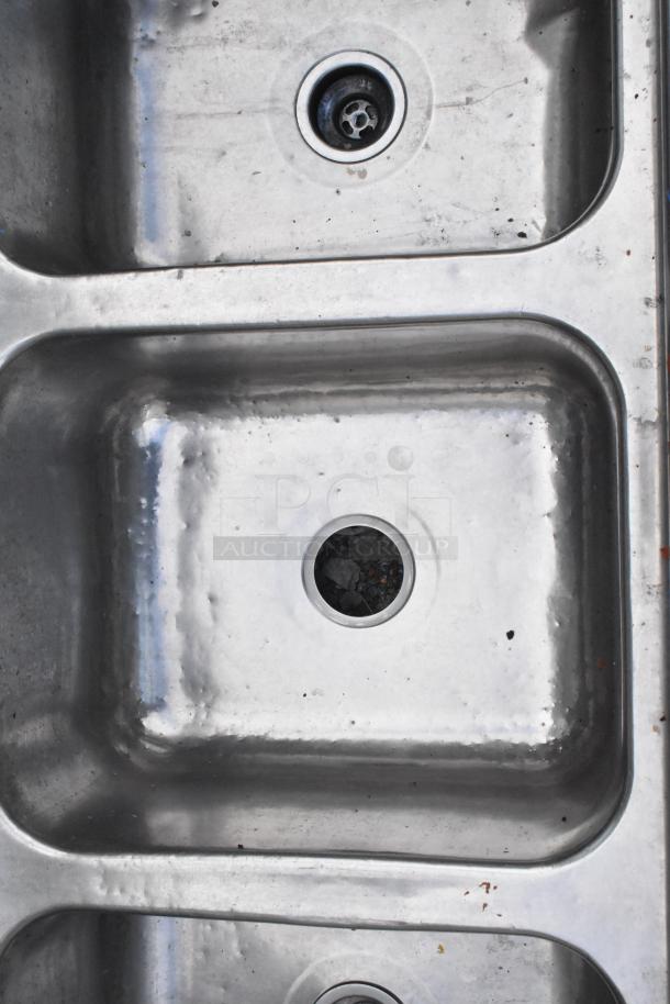 Stainless steel 3 bay sink without legs, features three large basins. Visible wear, ideal for commercial use.