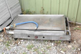 Wolf stainless steel commercial countertop flat top griddle, natural gas powered, with visible connector hose; used condition.
