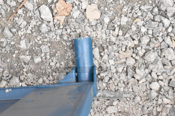 Blue metal flat cart with visible scratches and dents on gravel background. New condition despite minor blemishes.