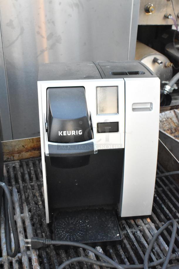 Keurig single cup coffee machine, silver, countertop model, 120 volts, visible wear, "Brew" button, two machines for auction.