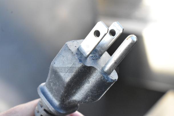 Close-up of a standard 120-volt power plug, part of a Keurig countertop single cup coffee machine.