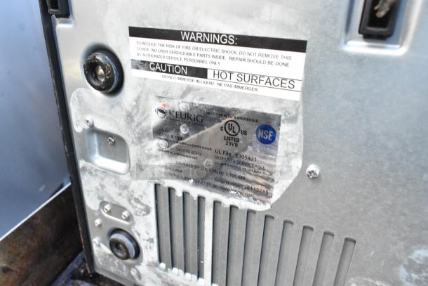 Keurig K150 coffee machine label showing model, voltage, and safety warnings. 120V, 1 phase, NSF certified.