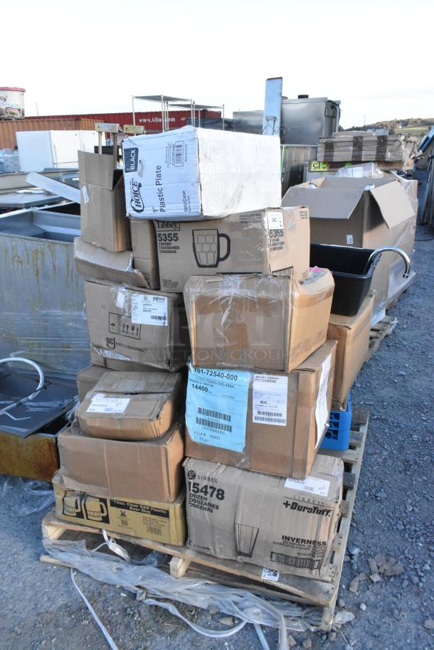 Stack of boxes labeled with various brands like "Libbey" and "DuraTuff," containing new scratch and dent items including glasses and bins.