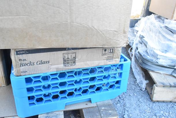 Box of Acopa 11 oz. Rocks Glasses stacked on blue drop-in bins, labeled with handling symbols, on a pallet. Scratch and dent condition.
