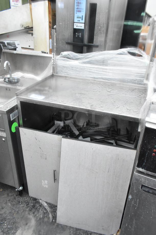 Stainless steel counter with under shelf, two doors, on commercial casters. Used condition, visible scratches and wear.