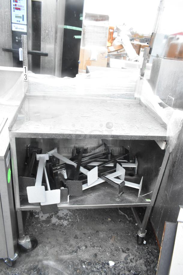 Stainless steel counter with under shelf and two doors on commercial casters, used condition, visible measurement markings.