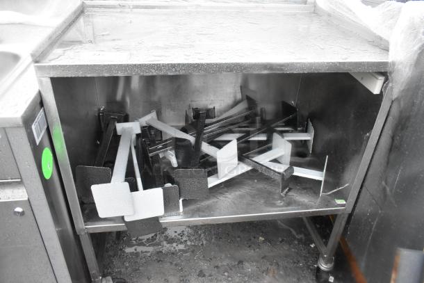 Stainless steel counter with under shelf and two doors, featuring commercial casters. Slight wear visible, ideal for restaurant use.