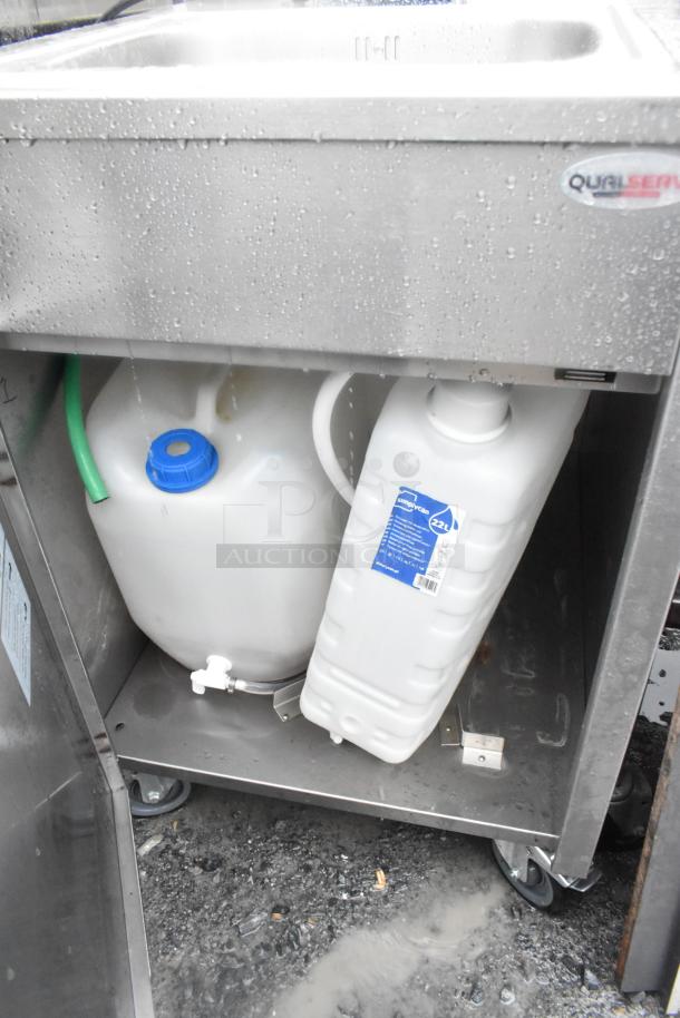 QualServ stainless steel portable sink with commercial casters, featuring water tanks and labels, in used condition.