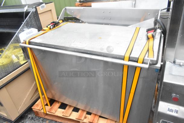Stainless steel commercial washing/soaking tub with yellow straps, mounted on a pallet, used condition.