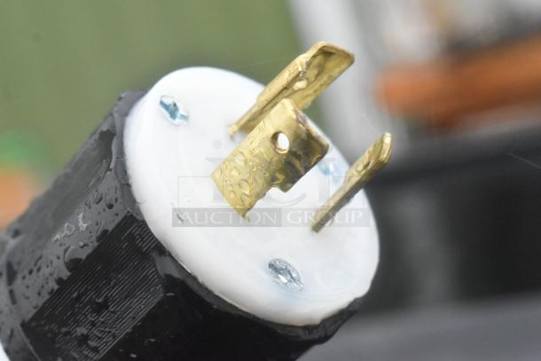 Close-up of electrical plug for Killion Metal Commercial Merchandiser. Gold prongs, white and black housing, wet with droplets.