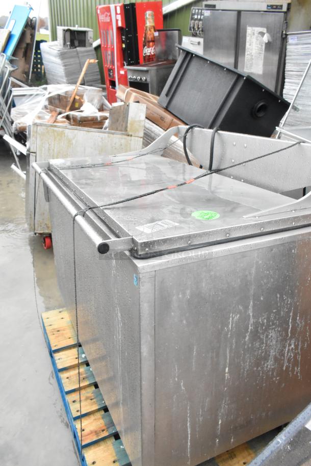 Stainless steel commercial washing tub on pallet, visibly wet, with barcode and inspection sticker, used condition.