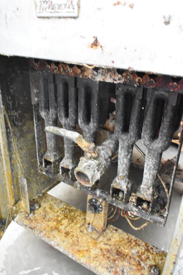 Migali stainless steel gas fryer, floor style with commercial casters, showing significant rust and wear.