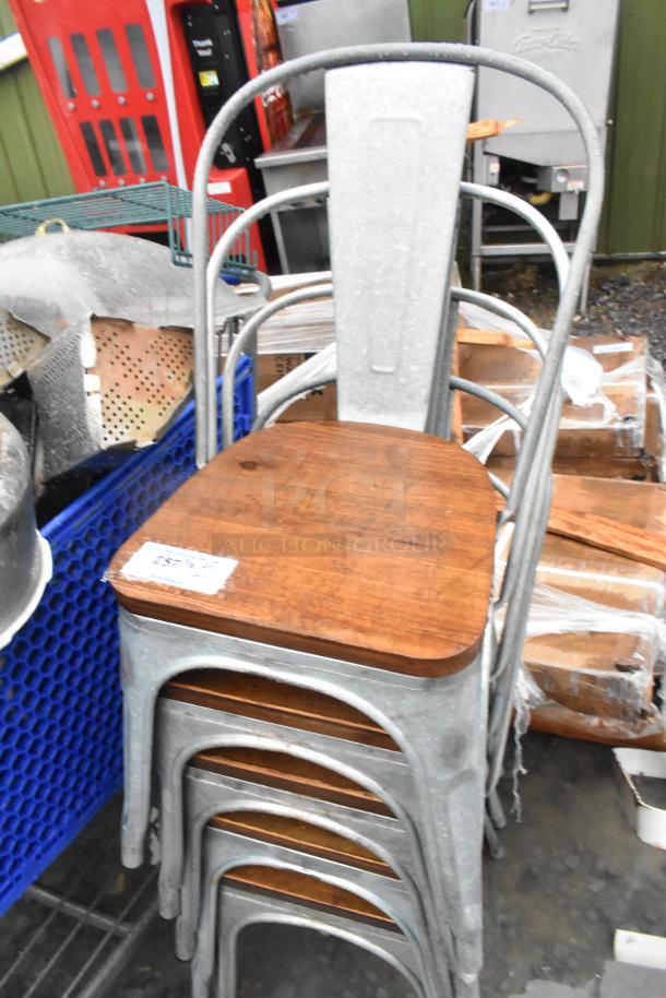 Stack of five gray metal dining chairs with wooden seats, in good condition. Each seat has a visible label with auction details.