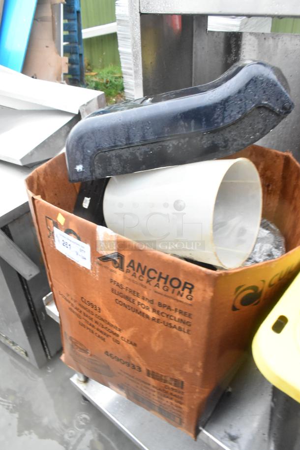 Box of mixed items including a napkin dispenser and a plastic bin. Box labeled "Anchor Packaging." Items are in used condition.