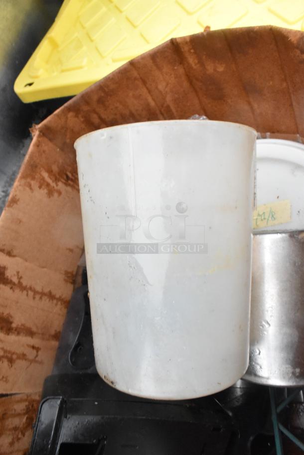 Lot of various items including a white plastic bin, napkin dispenser, and cardboard. Items show signs of wear.