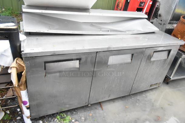 True TSSU-72-18 stainless steel commercial prep table with three doors. Visible wear, designed for sandwich/salad prep.