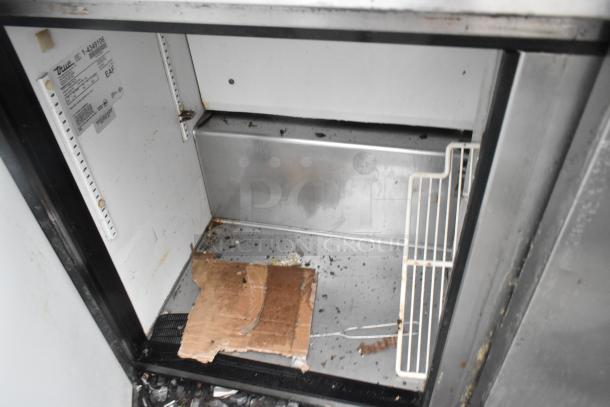 True TSSU-72-18 stainless steel commercial prep table, interior view, showing evidence of wear and debris. Model label visible.