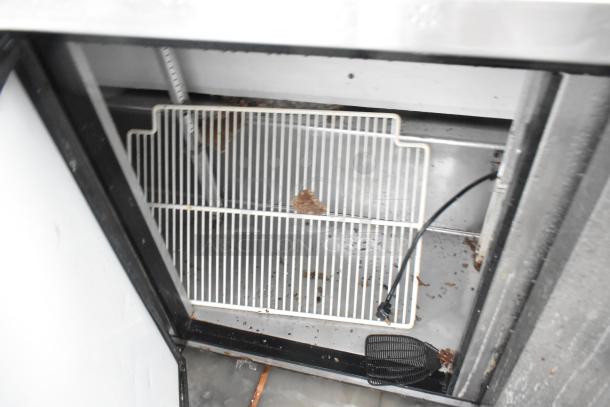 True TSSU-72-18 stainless steel commercial prep table, interior view. Includes shelving, wiring visible. Signs of wear.