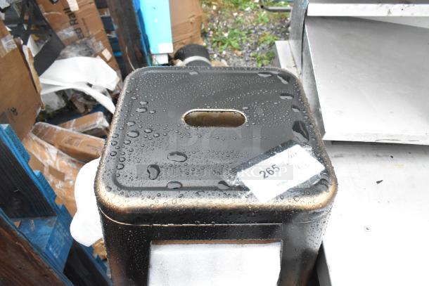 3 brand new scratch and dent black metal Tolix style bar stools, wet with raindrops, with auction label "265".