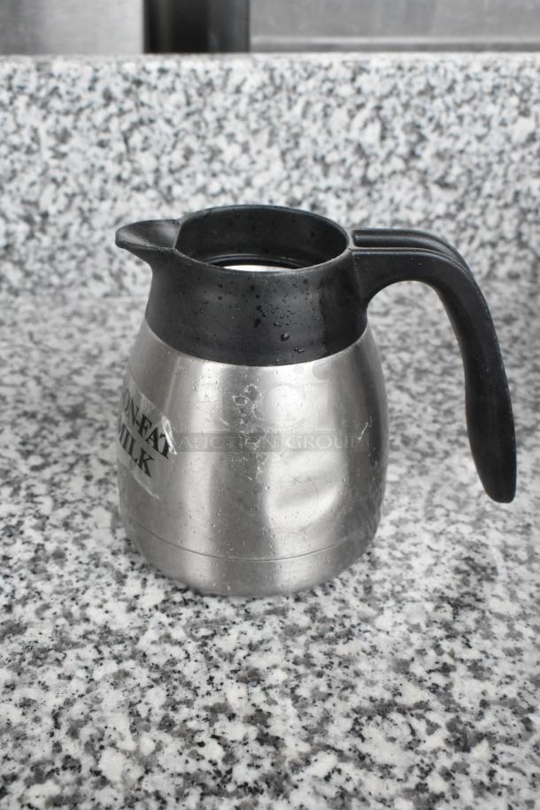 Metal pitcher with black handle and spout, labeled "Non-Fat Milk." Stainless steel body, used condition. Auction lot of 15.