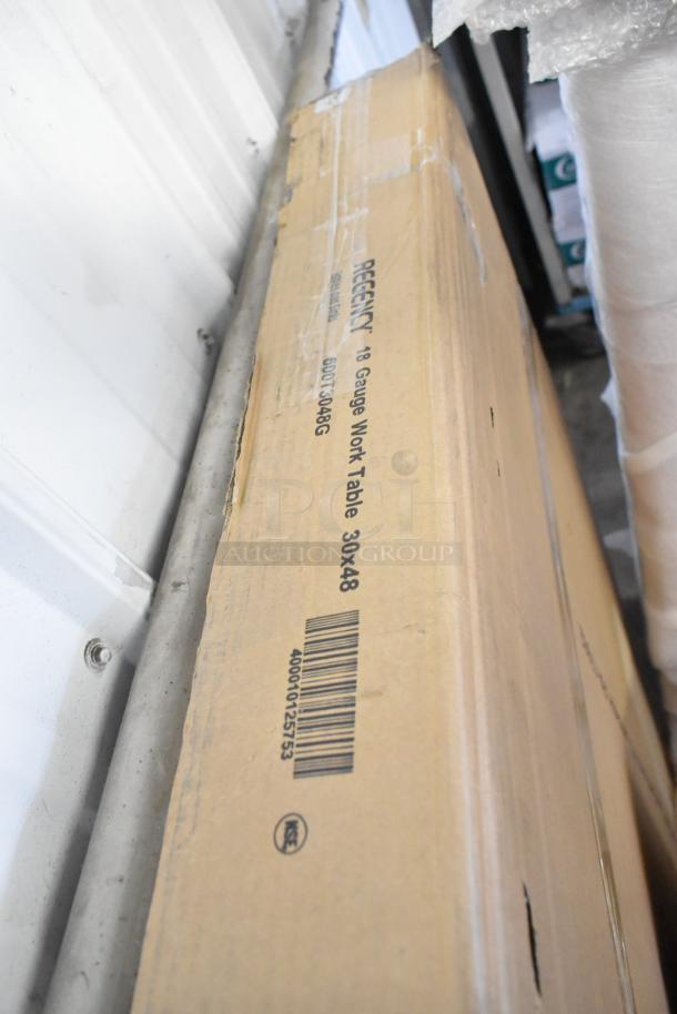 Box labeled "Regency 600T3048G Stainless Steel Table, 30x48" with visible barcode and markings, in new condition.