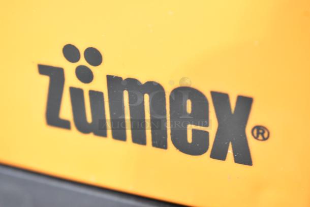Zumex MINEX Citrus Juicer logo close-up on bright yellow surface, indicating brand authenticity.
