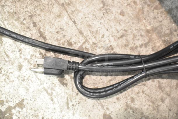 Coiled power cord of Avantco 177CO16 countertop convection oven, showcasing a 120V plug on a concrete surface.
