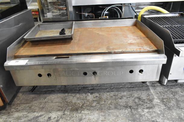 Stainless steel commercial gas griddle with flat top, used condition, countertop model, ventilation holes visible.