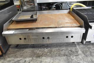 Stainless steel commercial gas griddle with flat top, used condition, countertop model, ventilation holes visible.