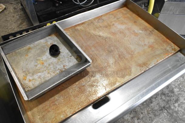 Stainless steel commercial countertop gas-powered flat top griddle, used condition with surface wear, includes drip tray.