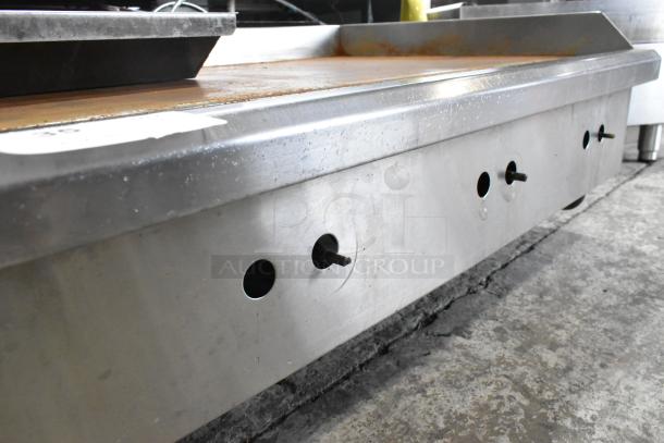 Stainless steel commercial countertop gas griddle, used, with a flat top and control knobs, showing signs of regular use.