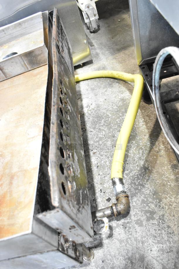 Stainless steel commercial countertop gas griddle with flat top, visible wear. Includes yellow gas hose attachment.