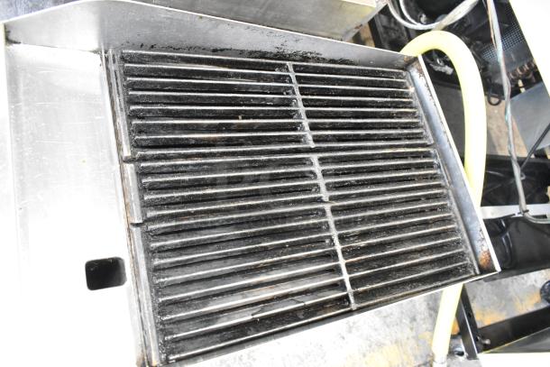 Globe stainless steel gas charbroiler grill, commercial countertop model, visible wear, sturdy grates, and gas connection.