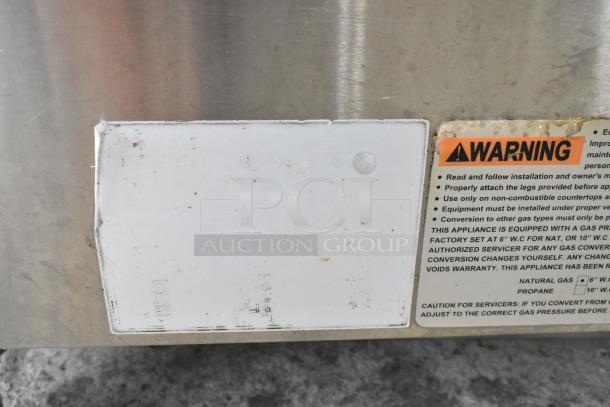 Globe stainless steel gas-powered charbroiler grill with visible warning label and clean surface. Ideal for commercial use.
