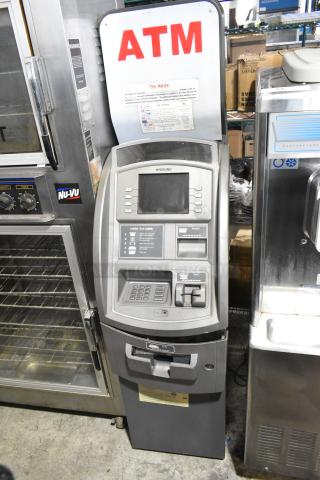 Hyosung metal floor-style ATM, featuring a digital screen and keypads. Marked "ATM" with fee notice sign. Good condition.