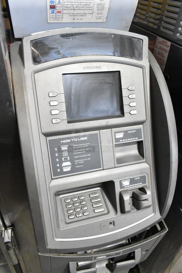 Hyosung Metal Floor Style ATM with touchscreen, card reader, keypad, and function buttons. Moderate wear, clear instructions.