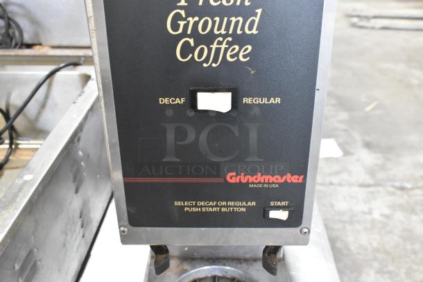 Grindmaster countertop coffee bean grinder, 120V, offering decaf and regular options, visible wear, "Made in USA" label.