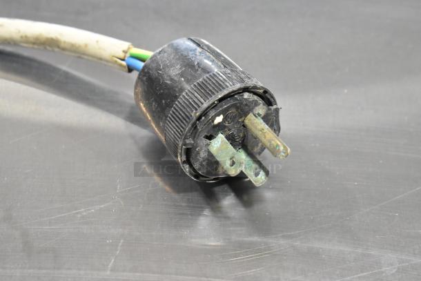 A close-up view of a used power plug with visible wear, connected to the Italgi machine, sitting on a metallic surface.