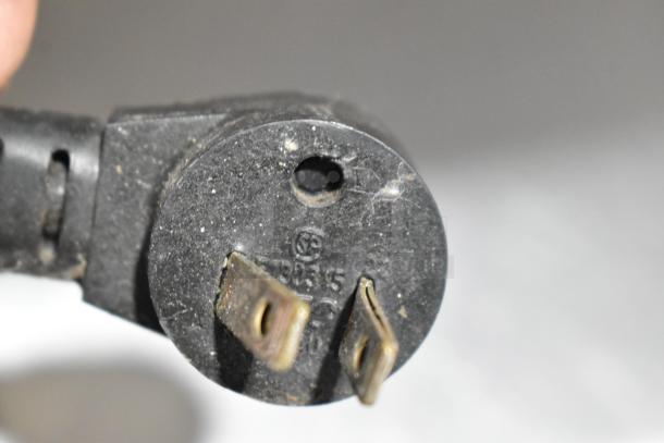 Close-up of the power plug for a Delfield stainless steel commercial sandwich salad prep table, showing plug prongs and markings.