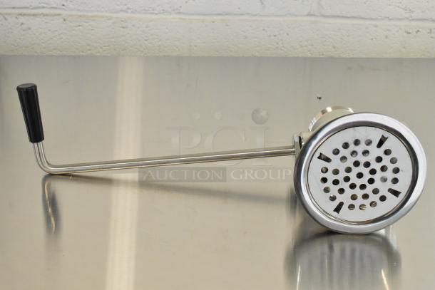 Stainless steel drain with long metal handle, brand new, with scratches and dents visible on surface.
