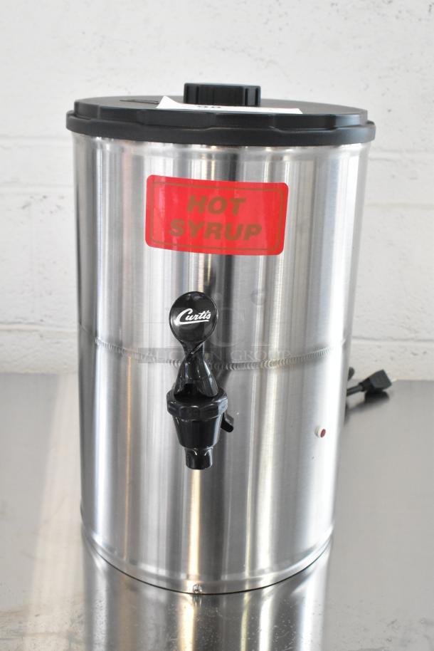 "Brand new Curtis SW-2 2-gallon stainless steel syrup warmer, marked 'HOT SYRUP,' 120V, with minor dents."