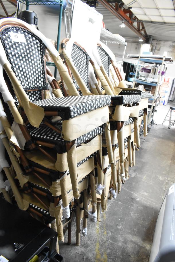 33 new Lancaster Table & Seating bistro chairs, black/white rattan weave, scratch and dent condition, stacked in warehouse.