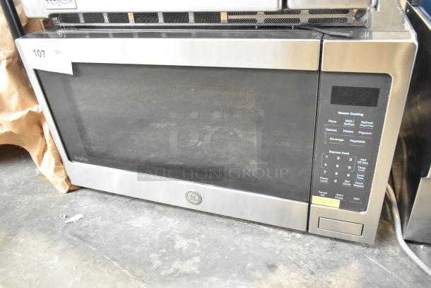 Brand new GE PCST22U1W1SS microwave oven, showing minor scratches and dents; features sensor cooking panel.