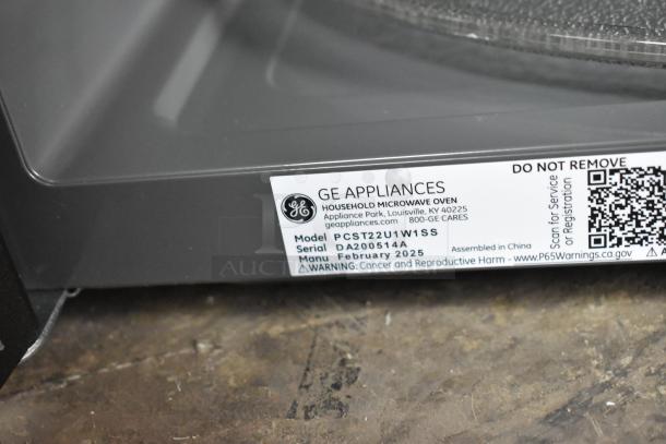 Brand new 2025 GE PCST22U1W1SS microwave oven with plate, scratch and dent, model details and warnings visible.