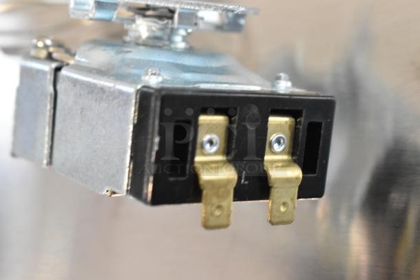 Electrical component close-up with metal connectors. Part of auction featuring 4 new scratch and dent items, including burner and circuit board.