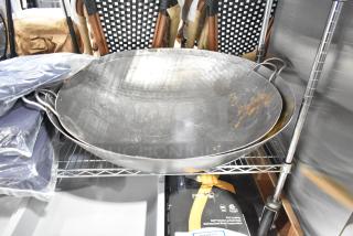 Two brand new metal woks with handles, showing visible scratches and rust marks. Sold as scratch and dent items.